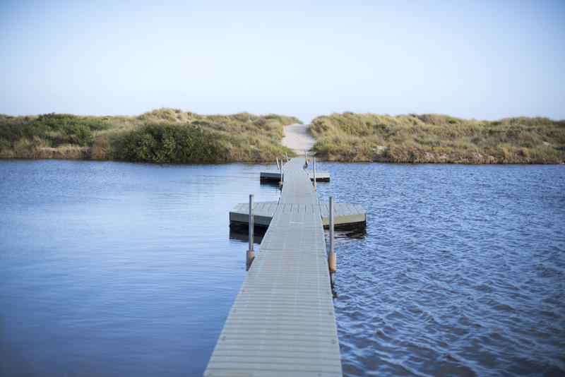 Empty long floating pedestrian bridge crossing separating water surface in two parts