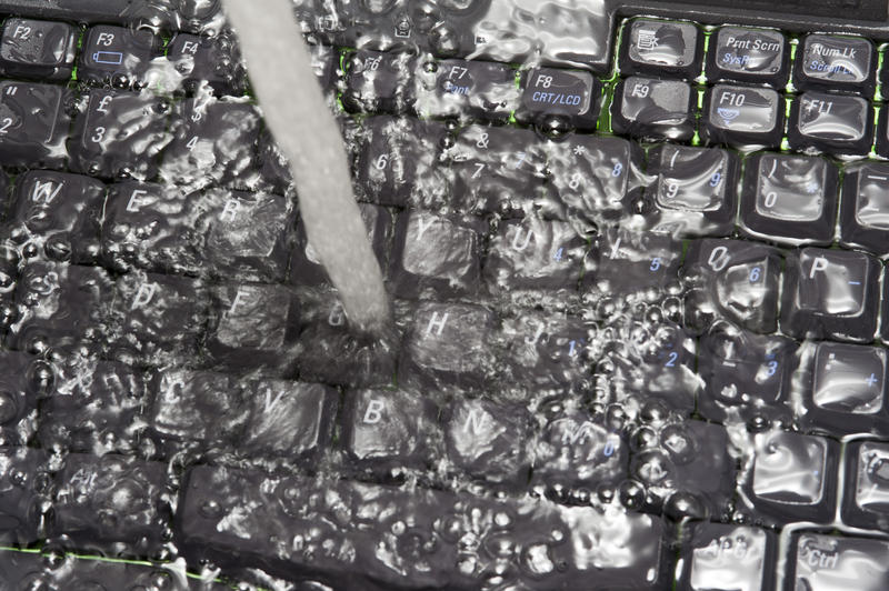 Close-up on personal computer black keyboard under running water, as electronics damage or virus removal concept