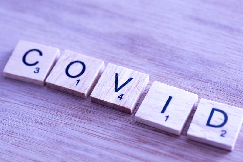 The word Covid in letters on wooden blocks from a word game in a high angle view on wood with copy space