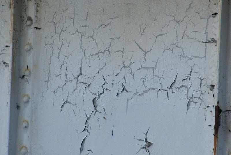 Old peeling cracked white paint on metal or wood panel in a close up background texture
