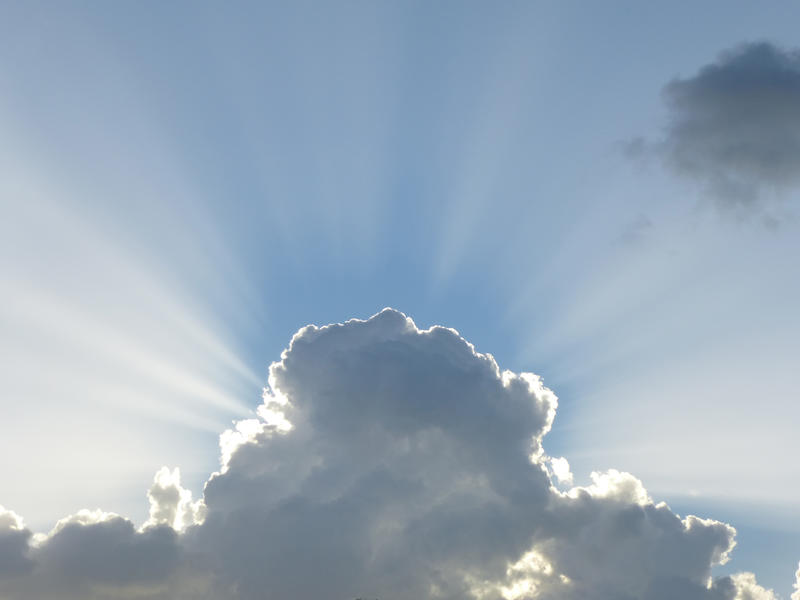 beams of ethereal sunlight emerging from behind a storm cloud