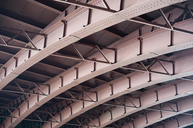 Architectural and structural engineering background of a curved steel arc formed by bridge trusses in a full frame view