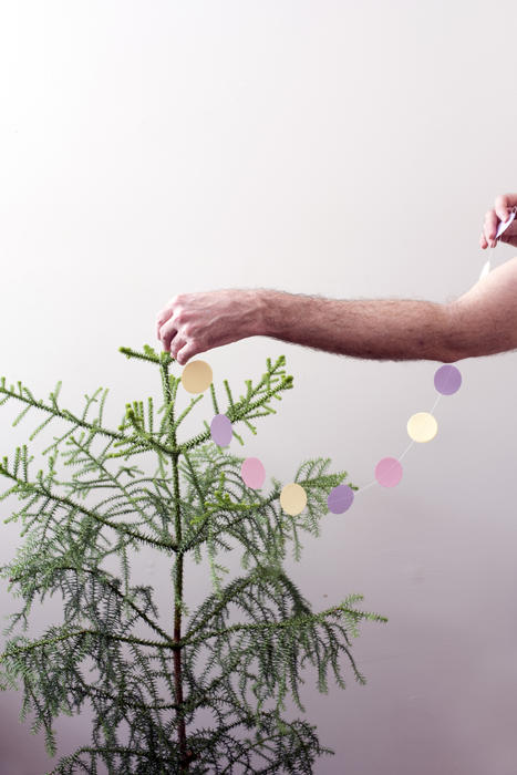 putting eco friendly paper decorations onto a small living christmas tree