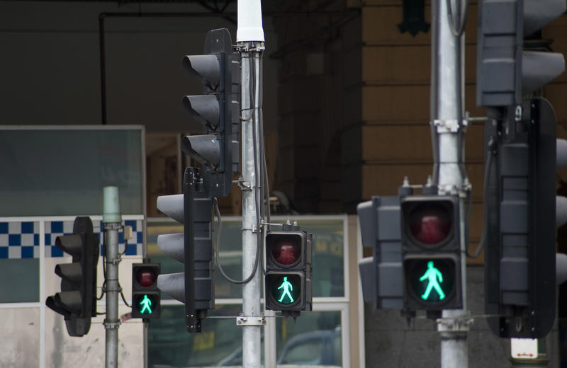 Easing of SOcial Distancing Concent: Three traffic lights with green pedestrian man sign showing it is safe to walk across the intersection in the street