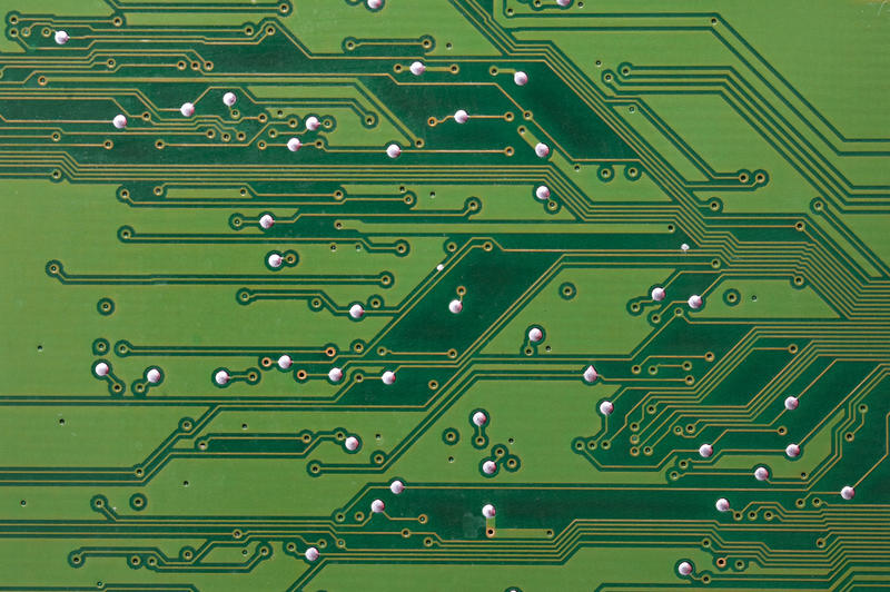 Electronics backdrop of green printed circuit board with conductive tracks in a full frame view