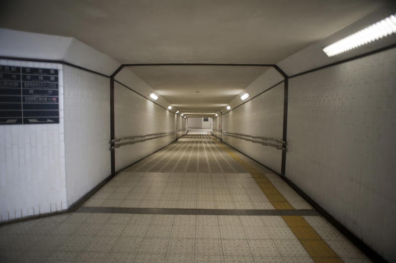 Empty modern subway tunnel with neon lights and tiled floor receding into the distance in a concept of the travel ban during Covid-19 pandemic