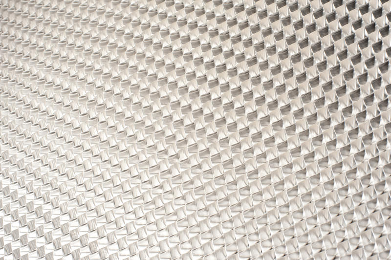 Background texture of a new shiny silver patterned textured metal grid in an exhaust filter in a close up full frame view