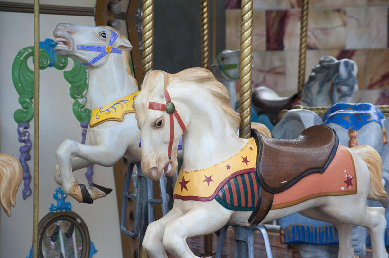 Close up detail of colorful carousel horses on a merry-go-round at a fairground or amusement park