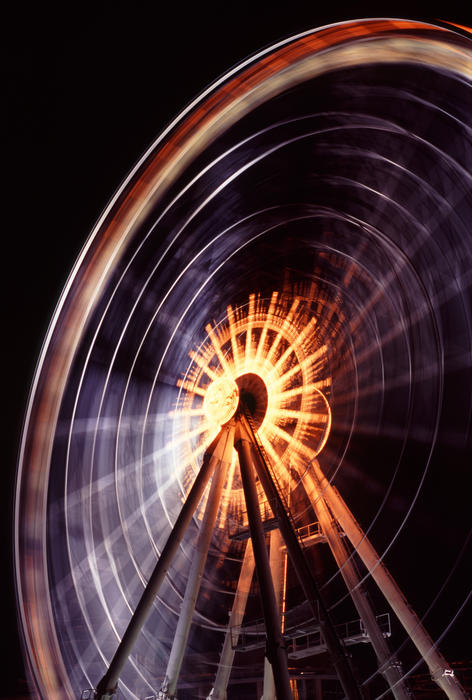 A long exposure, night time shot of a ferris wheel in motion.