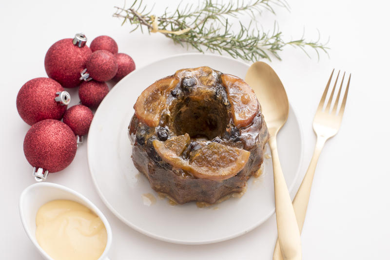 a contemporary white christmas table setting with plum pudding and gold cutlery