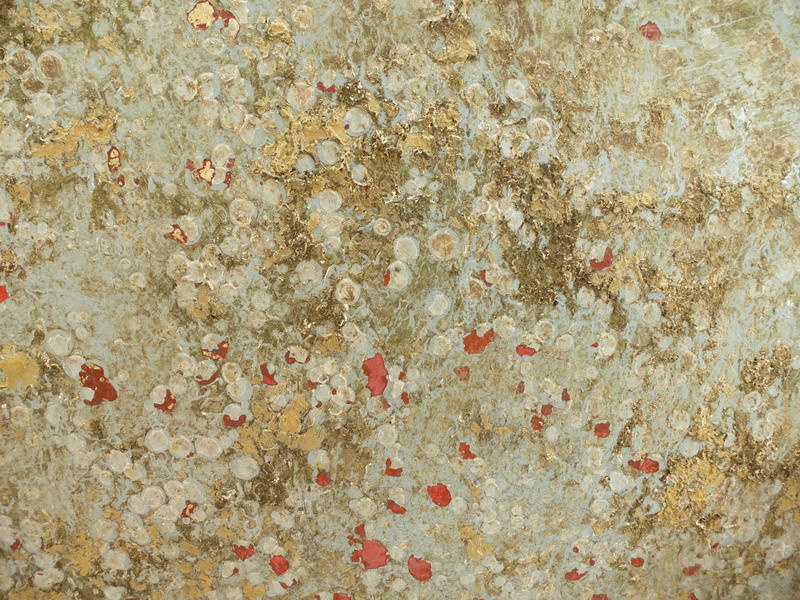 Background texture of a grunge dirty surface with mottled pattern and blotches of red in a full frame view
