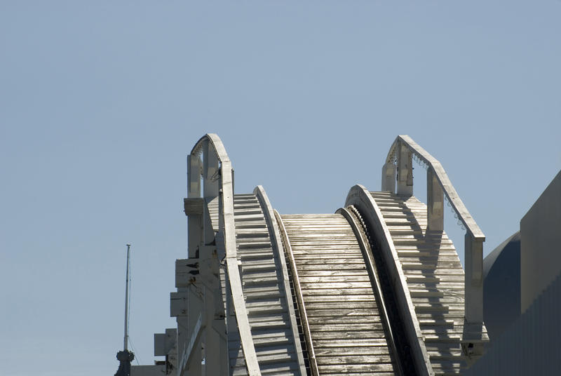 Cresting a hill on a rollercoaster ride with the empty track ahead against a blue sky