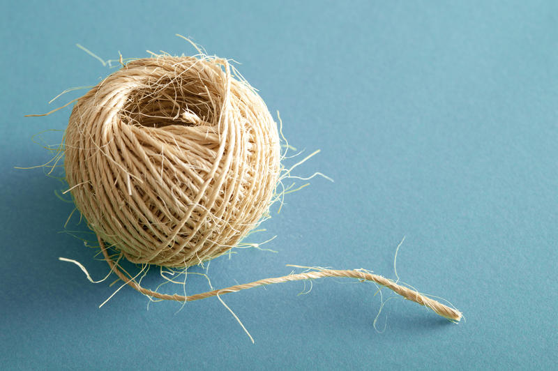 How Long concept showing a ball of natural fibre twine over a blue background with copy space