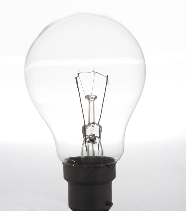Unlit incandescent electric lightbulb in close-up on white background as an idea or eureka concept