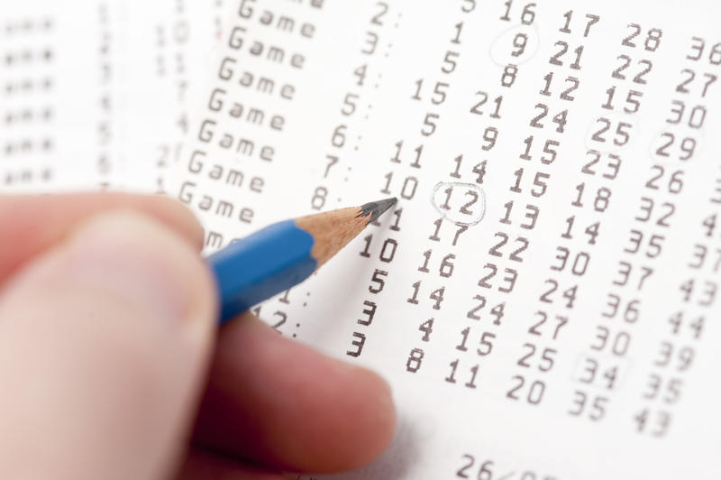 Person selecting lottery numbers on a card circling them with a pencil conceptual of games of chance and luck