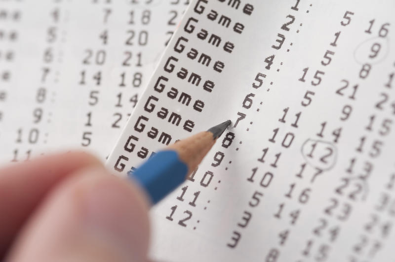 Checking for game results, circling numbers with pencil on lottery ticket. Close-up selective focus image