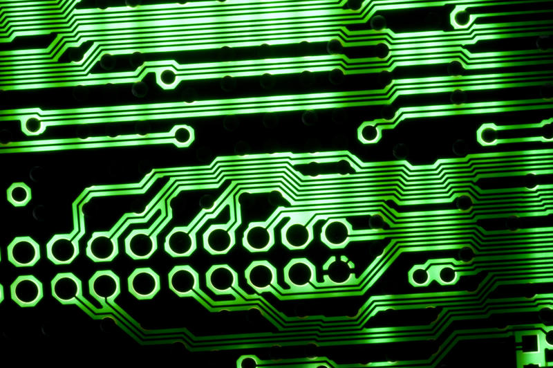 A close up macro shot of a back lit, green and black circuit board.