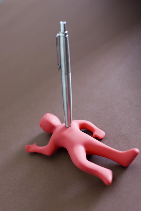 Management concept with stabbed pink figure of a man lying dead on the floor with a pen penetrating his heart, with copy space
