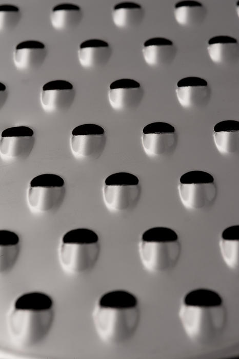 A close up, macro shot of sharp blades on metal food grater.