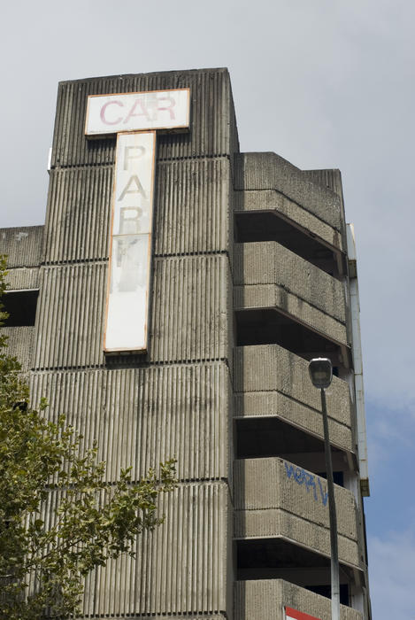 A vertical shot of an old concrete high rise car parking building.