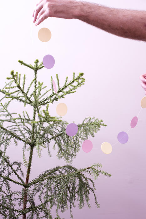 a person decorating a christmas tree with a paper garland