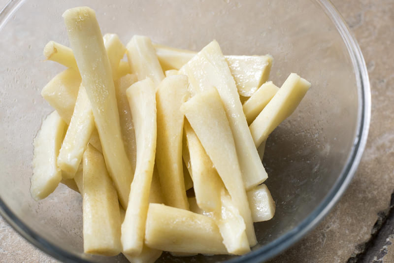 Fresh raw cleaned sliced parsnip wedges in a bowl during preparation for dinner