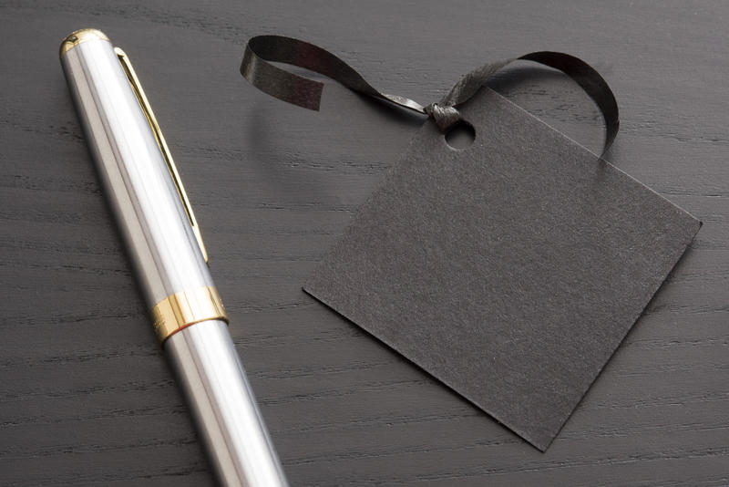 a blank black coloured gift tag and ribbon with a pen waiting to be written
