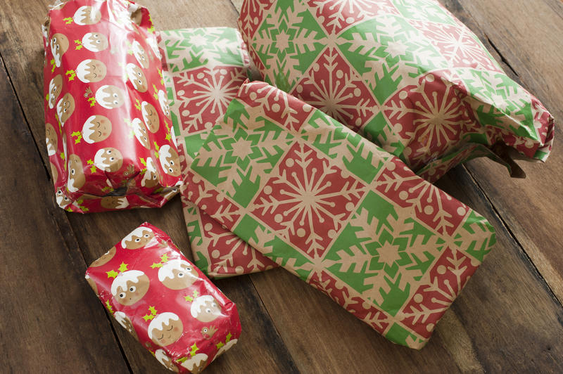 Pile of colourful gift-wrapped Xmas presents on a wooden floor read to celebrate on Christmas morning in a close up view