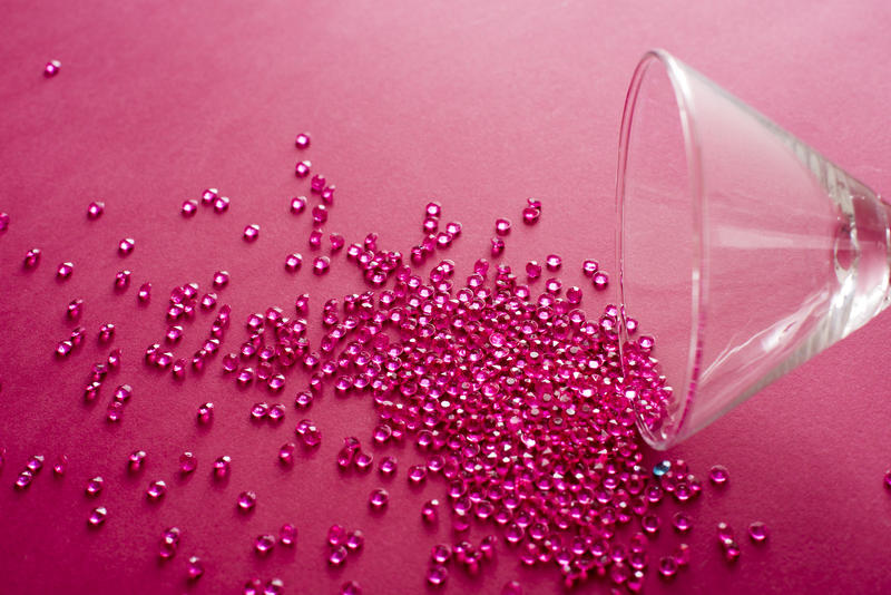 Red party background with spilled martini cocktail concept with a glass lying on its side spilling red beads onto a matching red background