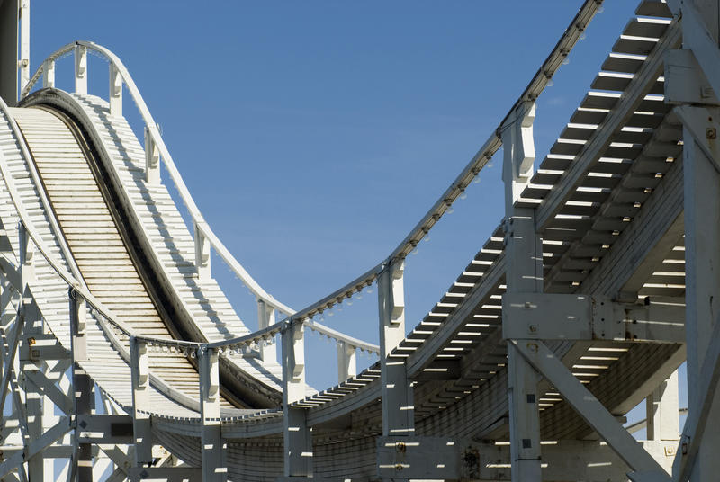 Big empty dip or valley on a rollercoaster track viewed against a sunny blue sky