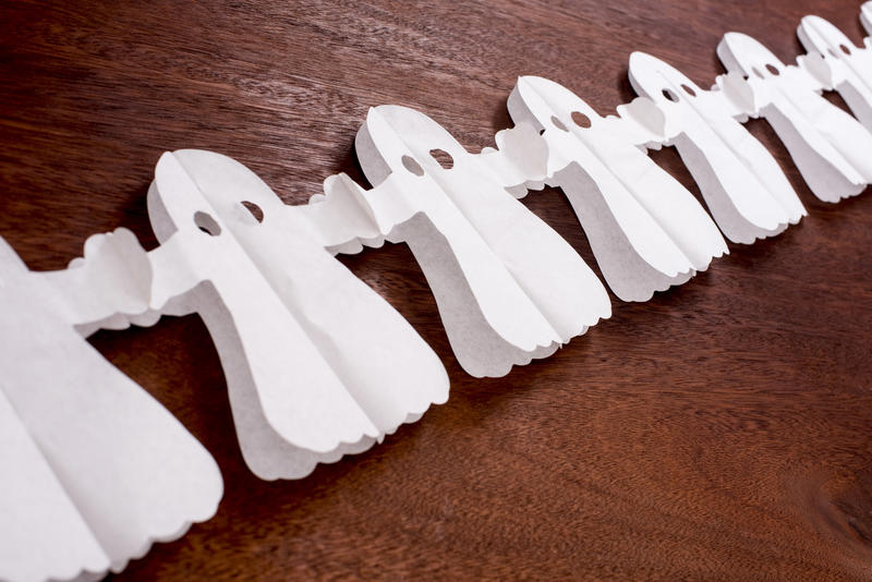a line of paper chain halloween ghost decorations holding hands