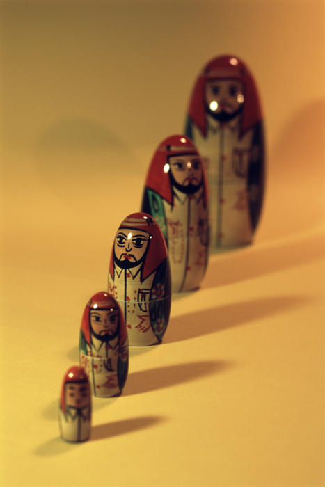 Set of separated Russian Babushka nesting dolls arranged in ascending order of size over a yellow background with shadows and copy space
