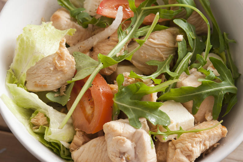 Healthy salad with chicken, tomatoes and arugula, viewed from above in close-up