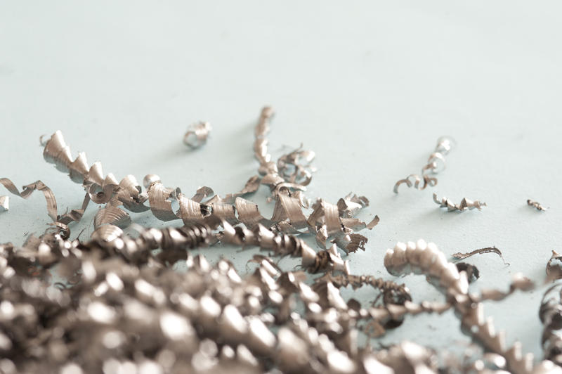 A close up, detailed shot of shaved metal swarf on a plain blue background with copy space.