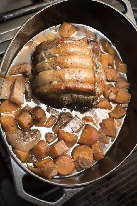 Cooking a beef shoulder casserole or ragout with vegetables in a high angle view of the meat inside a cast iron pot