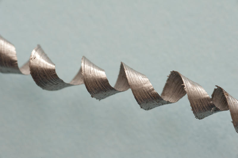 Close up detail of spiral of shaved steel swarf on a plain background with copy space.