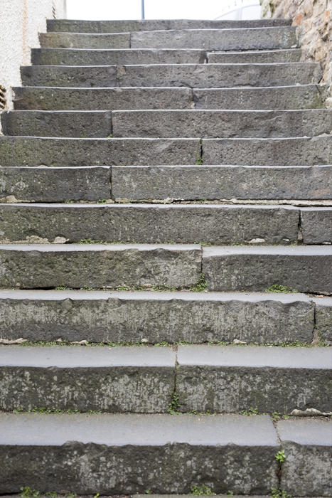 Standing at the bottom of a flight of external stone steps looking up towards bright daylight at the top in a full frame view