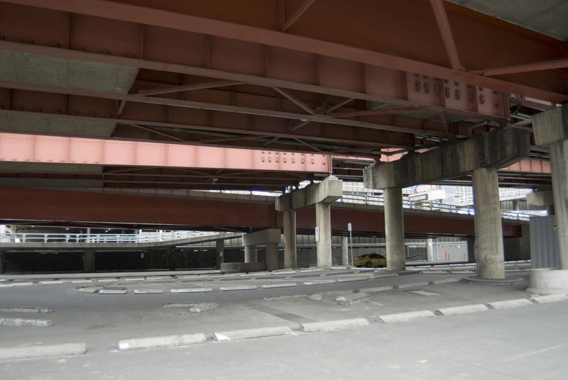 The space under multilane street overpass with red metal beams on concrete supports. Urban infrastructure background concept