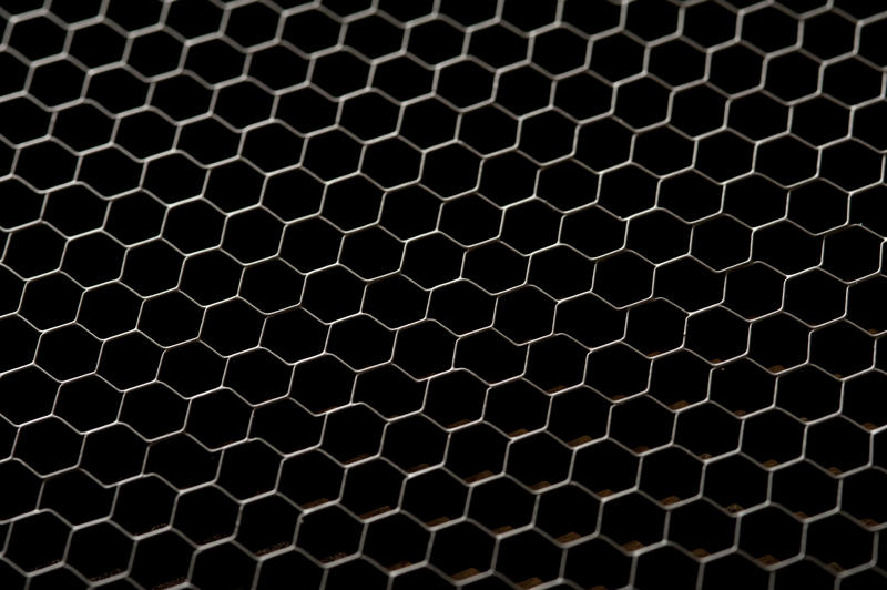 Chicken wire mesh fence over a black background in a concept of safety, security and privacy in a full frame view