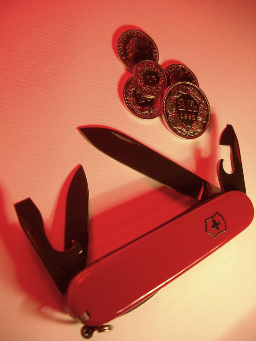 detail of the blades of a red swiss army knife and a selection of swiss coins