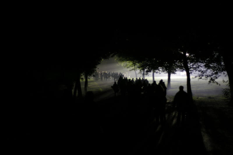 abstract and creepy nightime photography, a line of people walking through a park