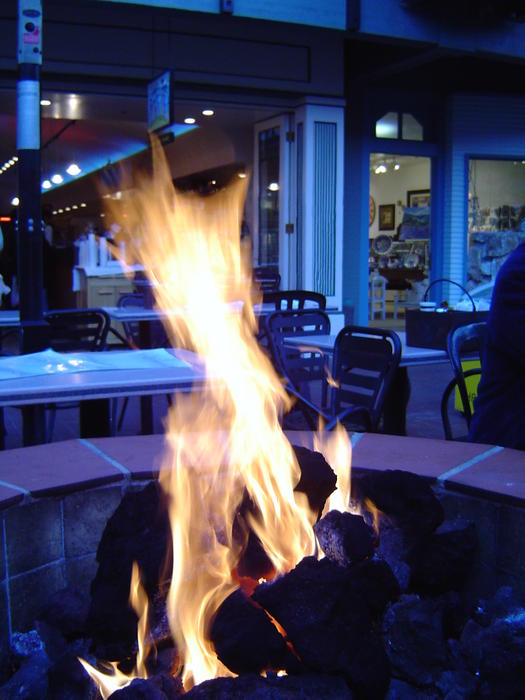 a flaming fire pit, out door heating at a street side restaurant