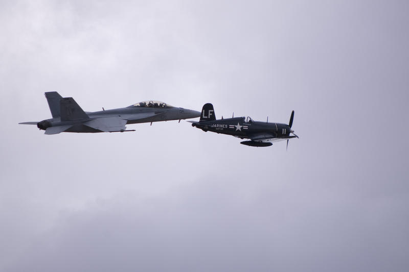a navy F4U Corsair and a FA18 jet flighter in flight, old an new together