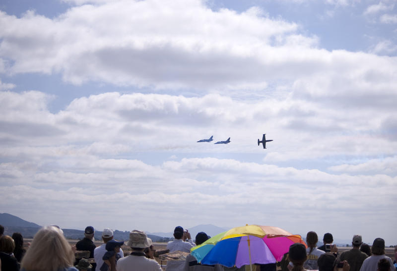 editorial use only : a line of people watching an aircraft flight display at an airshow