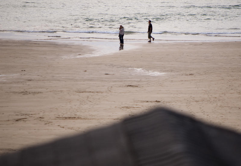a moody image of a couple of people walking along a beach