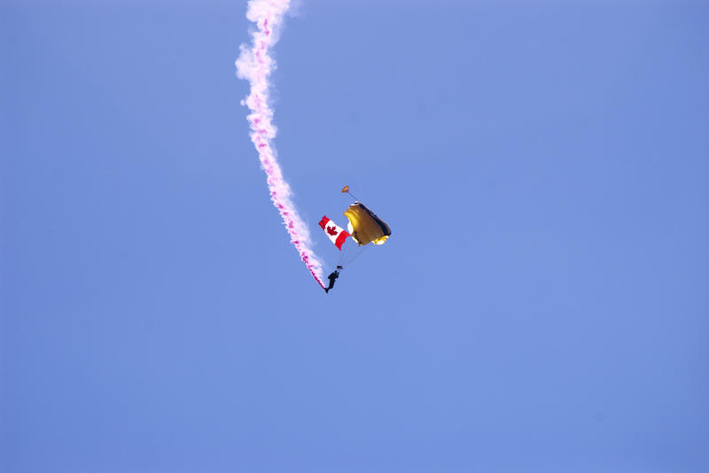 a paratrooper with a canadian flag at an air show
