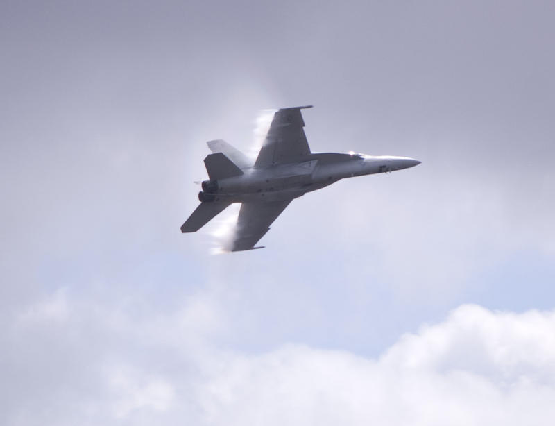 Boeing FA-18 Super Hornet multirole fighter aircraft with lines of vapour formed at the trailing edge of the wings