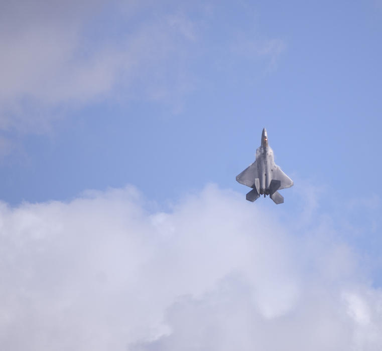 an F-22 Raptor plane climbing straight up in to the sky