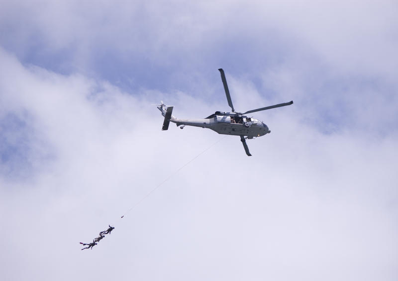 A helicopter with three divers 'flying' at the end of a line