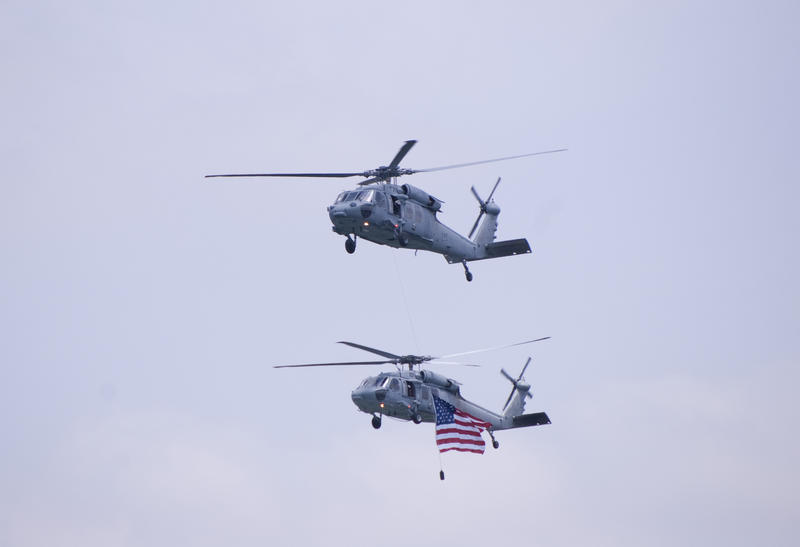 a couple of helicopters flying the strs and stripes at an air show